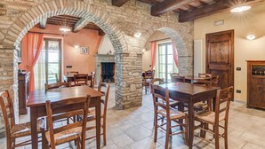 A rustic dining area with stone arches, wooden tables, and chairs. - Holiday Home in Urbania With Hill Views (Urbania)