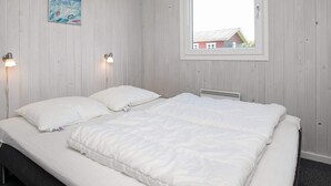 A bedroom with a double bed, two bedside lamps, a window with a view of a house, and a painting on the wall. - 6 Person Holiday Home in Lokken (Lokken)