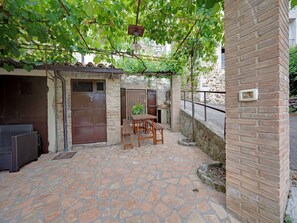 Une terrasse avec un sol en pierre, une table en bois et des chaises.