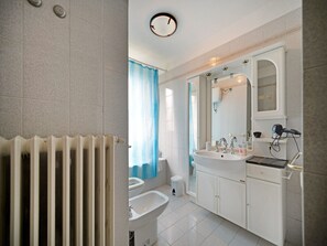 Une salle de bain équipée d’un radiateur, d’un bidet, d’un lavabo et d’un miroir.