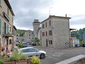 Rua com edifícios de pedra, um carro e uma placa indicando direções para Orvieto e Orvieto 20.