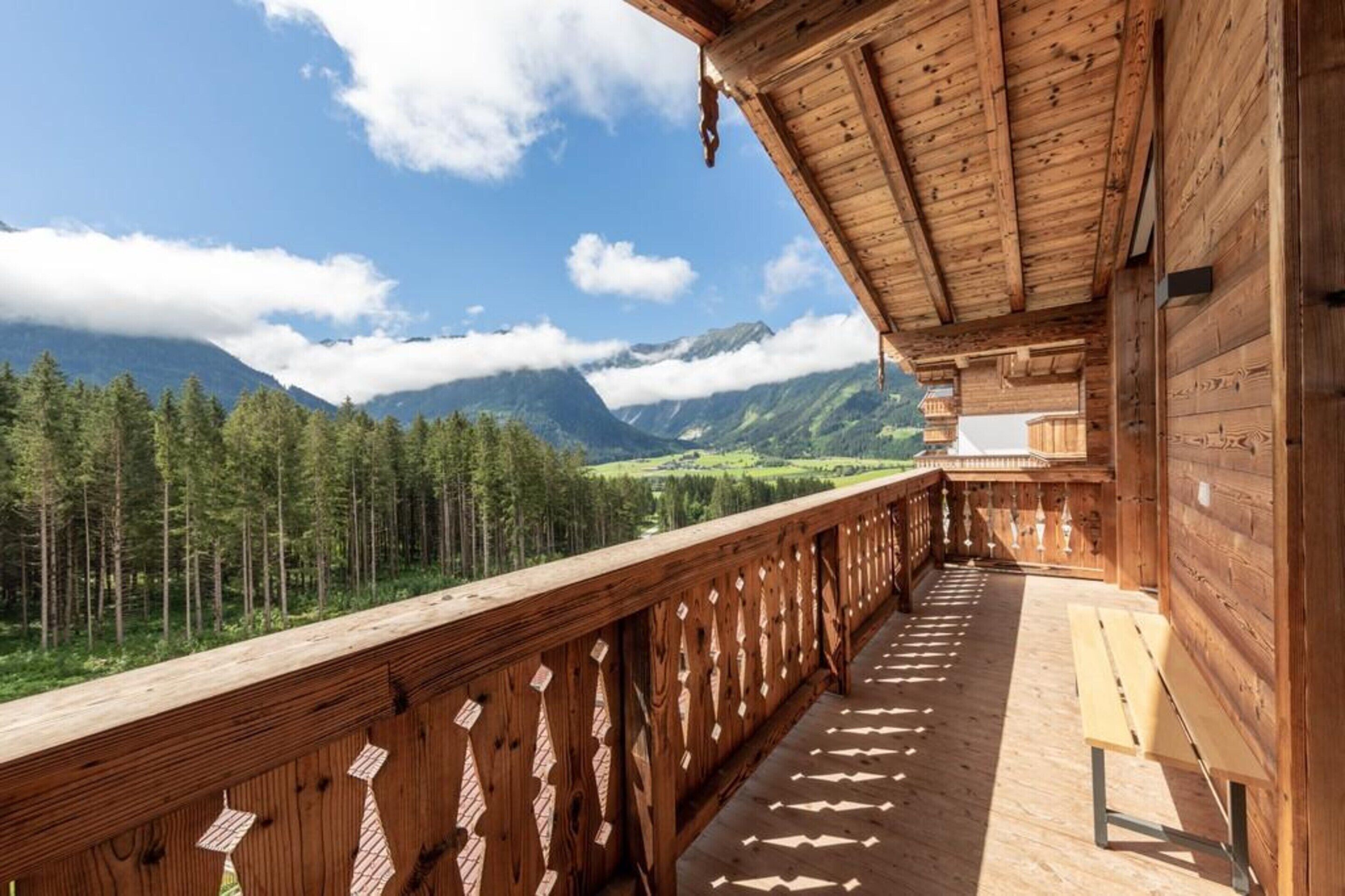 Een houten balkon met uitzicht op een bos en bergen.