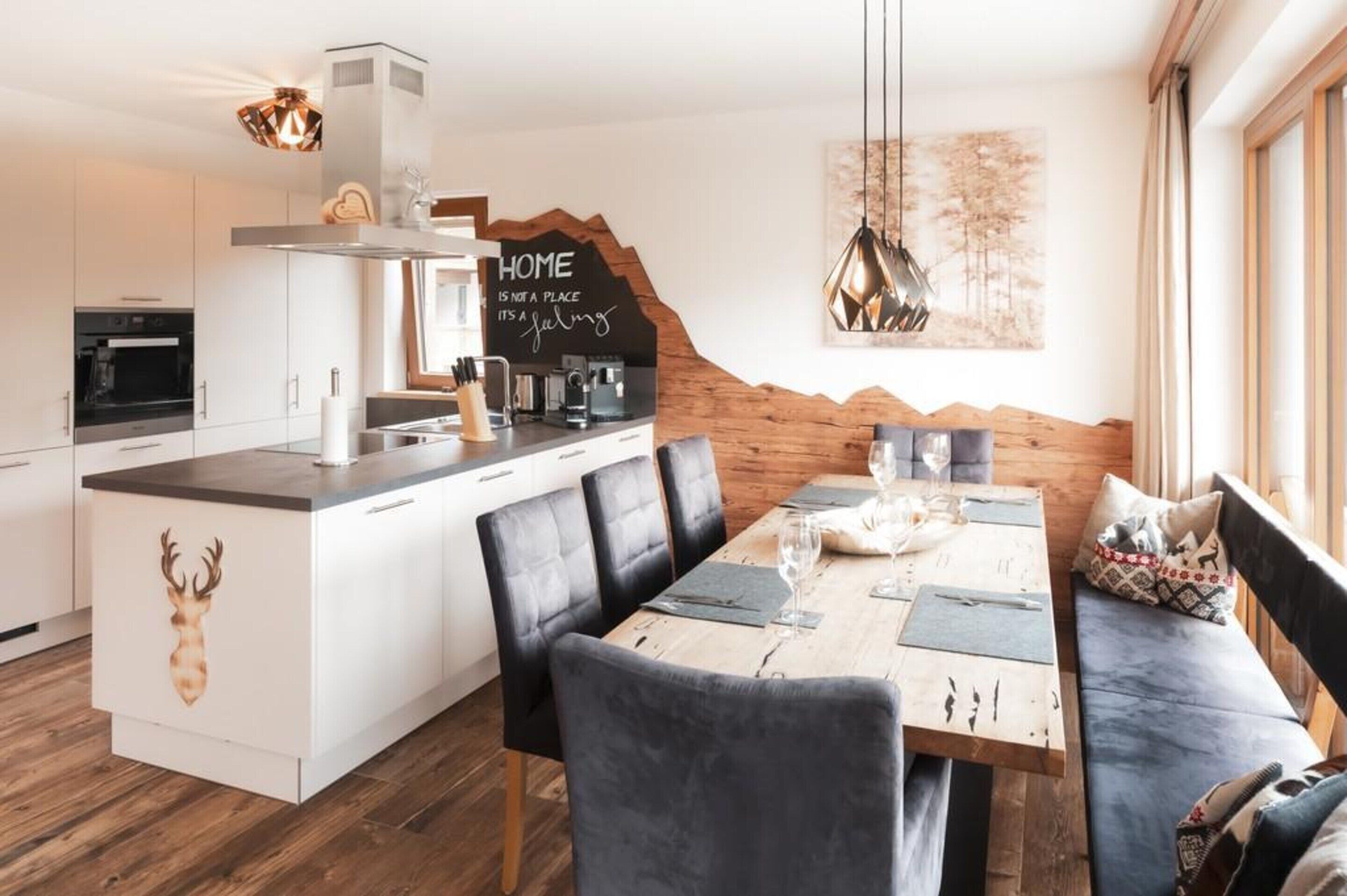A modern kitchen with white cabinetry, a built-in oven, and a dining area with a wooden table and black chairs.