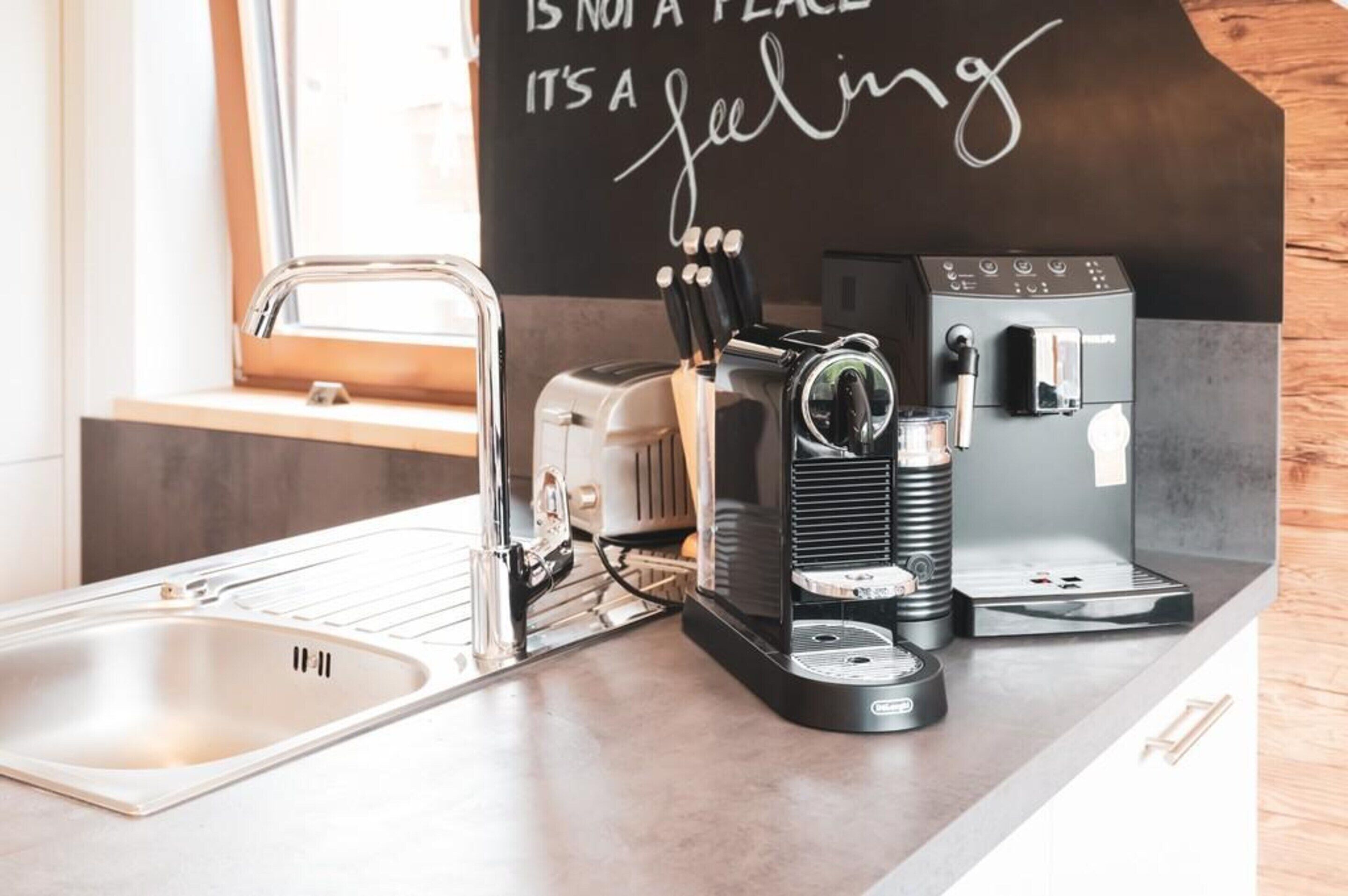 A kitchen with a coffee machine, a toaster, and a sink.