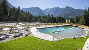 A swimming pool with a wooden deck, surrounded by a wooden fence and trees. - Splendid Chalet in Neukirchen near Wildkogel Ski Arena (Neukirchen am Grossvenediger)