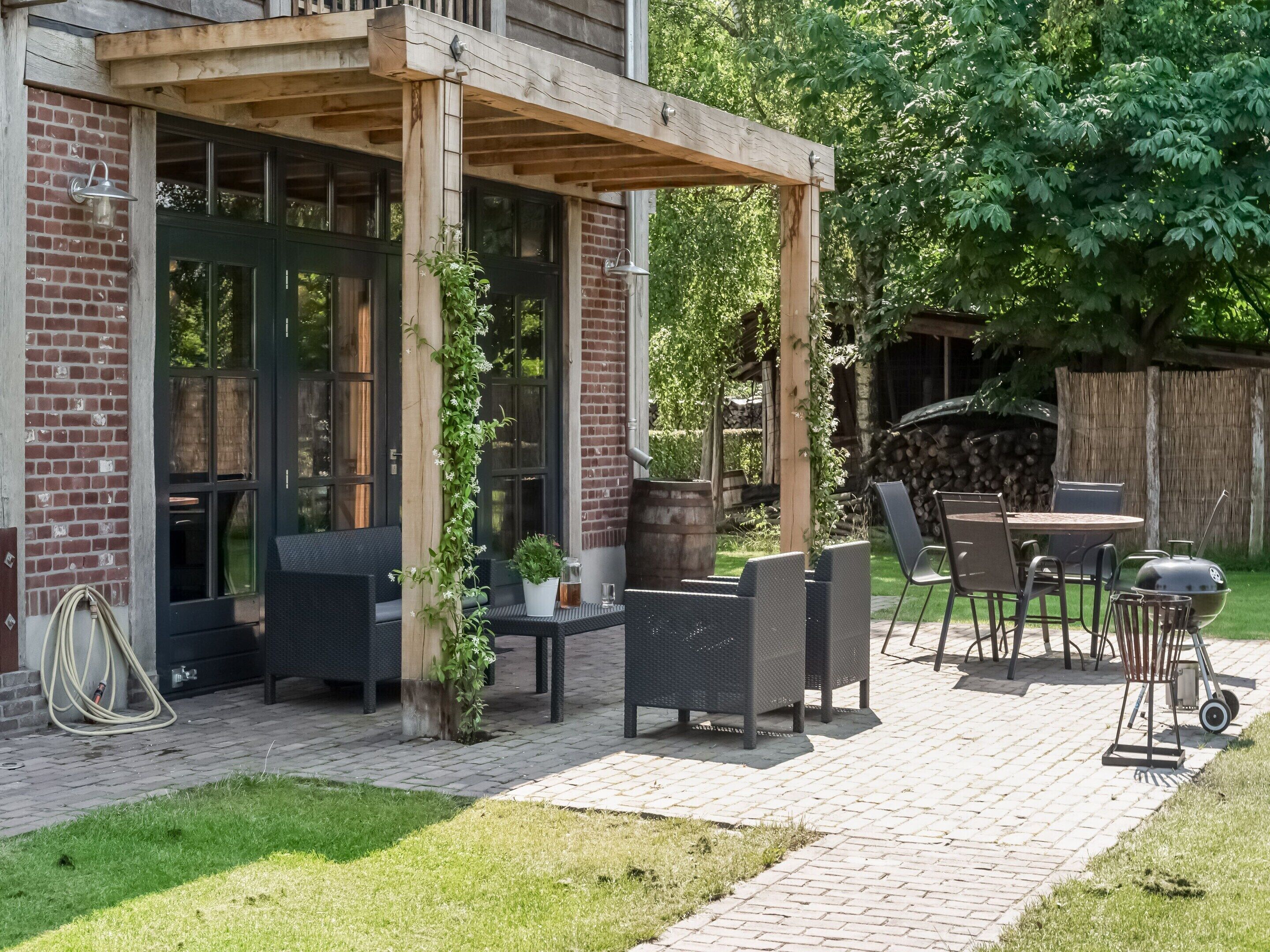 A patio area with outdoor seating, a barbecue grill, and a pergola structure.