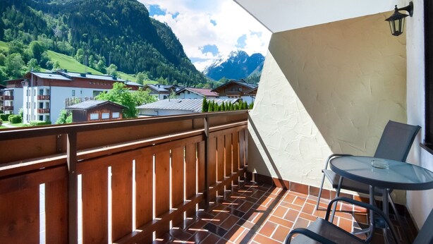 A balcony with a view of a mountain landscape, a table, and chairs. - Chalet in Kaprun Near Ski Slopes (Kaprun)
