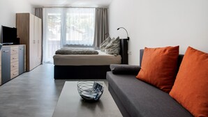 A modern, minimalist living room with a sofa, a coffee table, and a TV on a cabinet. - Chalet in Kaprun Near Ski Slopes (Kaprun)