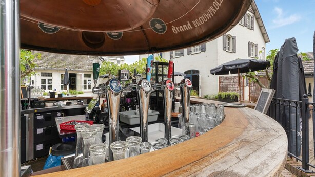 Un espace bar doté de plusieurs robinets, de verres et d’un comptoir en bois.