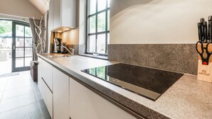 Une cuisine moderne dotée d’un grand îlot central, d’appareils électroménagers en acier inoxydable et offrant une vue sur l’extérieur.