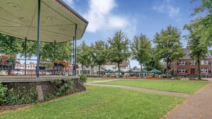 Un parc avec un kiosque, des bancs et un mur en briques.
