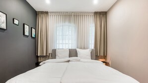 Une chambre d’hôtel moderne avec un grand lit, des murs gris et une fenêtre avec des rideaux.