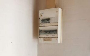 A white electrical panel with multiple switches and a label, mounted on a wall.