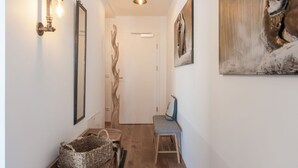 A hallway with a wooden bench, a woven basket, a wall-mounted light fixture, and a painting.
