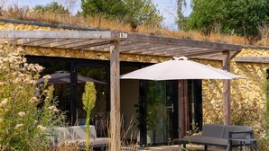 Ein überdachter Außenbereich mit Holz-Pergola, einer Bank und einem Sonnenschirm.