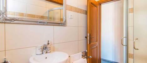A bathroom with a white sink, a mirror, and a shower area.