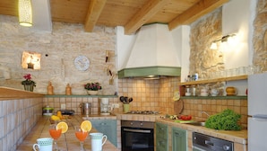 A kitchen with a stone wall, wooden beams, a gas stove, and a sink. - Villa in Batlug With Private Pool (Gracisce)