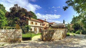A stone-walled building with a gravel driveway leading to a gated entrance. - Villa in Batlug With Private Pool (Gracisce)