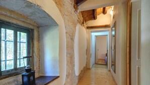 A narrow hallway with wooden flooring, a window with a view of trees, and a door at the end. - Villa in Batlug With Private Pool (Gracisce)