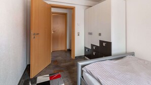 Ein Schlafzimmer mit Bett, Kleiderschrank und einer Tür zu einem anderen Raum.