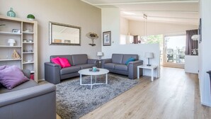Ein modernes Wohnzimmer mit zwei grauen Sofas, einem Couchtisch und einem Bücherregal.