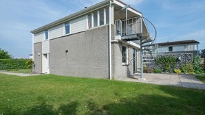 Ein modernes, zweistöckiges Gebäude mit Ziegelaußenwand, einem Balkon und einer kleinen Grünfläche.