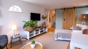 A modern living room with a sofa, a coffee table, a TV, and a staircase leading to another level. - Holiday Home in Medemblik With Garden (Medemblik)