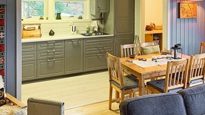 A compact kitchen with grey cabinets, a wooden dining table, and a cozy seating area. - 6 Person Holiday Home in Ostereidet (Alver)