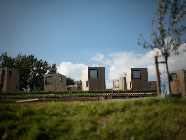 A modern architectural complex with multiple rectangular buildings, surrounded by greenery and under a clear sky. - Special Lodge With Great View, Near Maastricht (Gulpen)