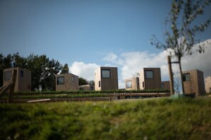 A modern building complex with multiple rectangular structures, some with windows, surrounded by greenery and a clear sky. - Special Lodge With Great View, Near Maastricht (Gulpen)