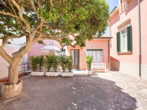 A courtyard with a tree, potted plants, a white umbrella, and a bench. - Holiday Gome in San Vincenzo Near Beach (San Vincenzo)