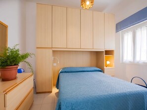 A bedroom with a bed, a dresser, a potted plant, and a window with curtains. - Holiday Gome in San Vincenzo Near Beach (San Vincenzo)
