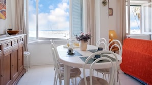 A dining area with a table and chairs, a sofa, a kitchen counter, and a view of the beach. - Holiday Gome in San Vincenzo Near Beach (San Vincenzo)