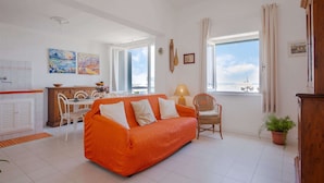 A bright living room with a sofa, a dining area, and a view of the beach. - Holiday Gome in San Vincenzo Near Beach (San Vincenzo)