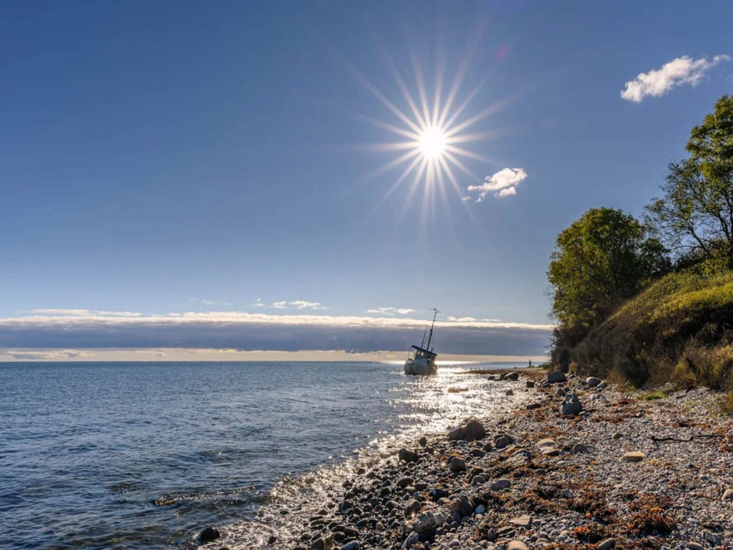 A rocky shoreline with a boat and a clear sky.