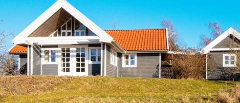 Une maison à deux étages, dotée d’un toit en pente et d’une grande véranda à l’avant.