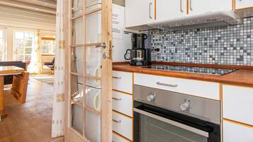 A kitchen with a tiled backsplash, wooden cabinets, a coffee maker, and a large oven.