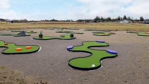 Un campo de minigolf con varios hoyos y un cielo despejado.