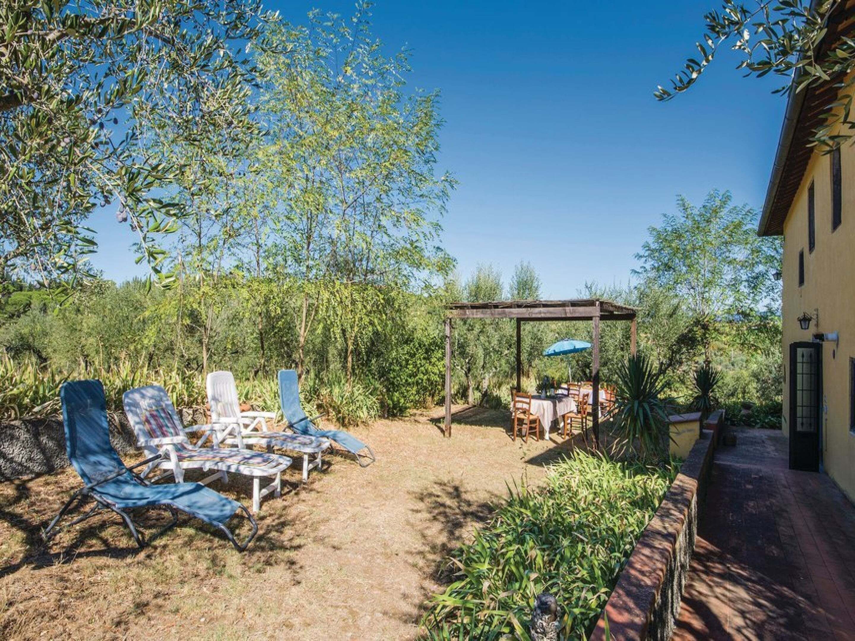 A patio with lounge chairs, a pergola, and a table set for dining.