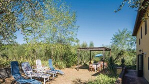 A patio with lounge chairs, a pergola, and a table set for dining. - Tuscany Bliss: Garden Retreat (San Casciano in Val di Pesa)