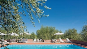 A swimming pool with lounge chairs and umbrellas, surrounded by trees. - Tuscany Bliss: Garden Retreat (San Casciano in Val di Pesa)