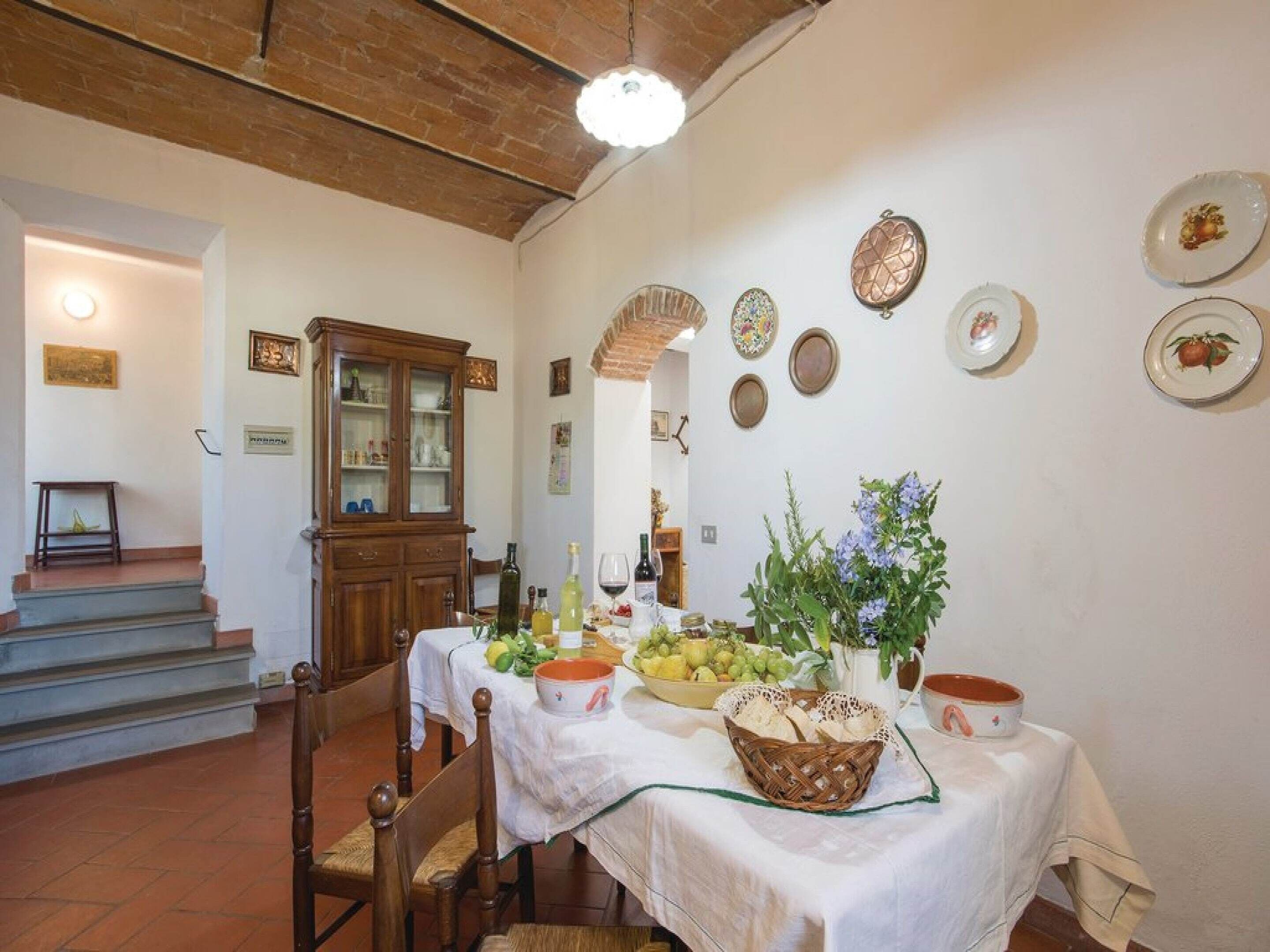A dining area with a table set for a meal, a cabinet, and a staircase leading to another room.