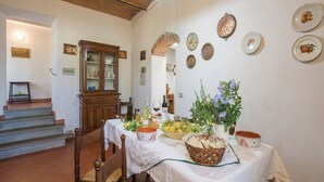 A dining area with a table set for a meal, a cabinet, and a staircase leading to another room. - Tuscany Bliss: Garden Retreat (San Casciano in Val di Pesa)