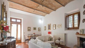 A living room with a sofa, a dining table, and a fireplace. - Tuscany Bliss: Garden Retreat (San Casciano in Val di Pesa)