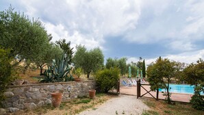 Un sendero de grava que conduce a una zona de piscina con un muro de piedra y plantas en macetas.