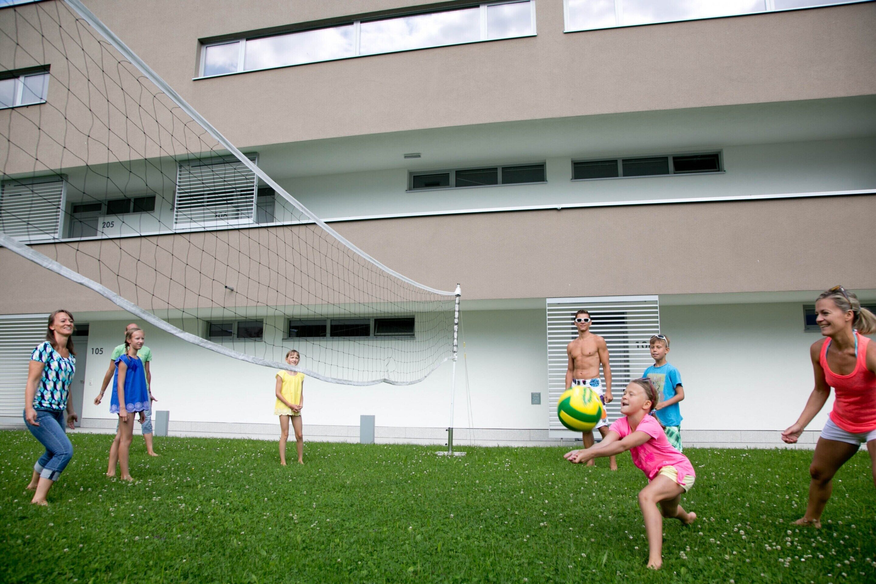 A group of people playing volleyball in an outdoor area with a net.