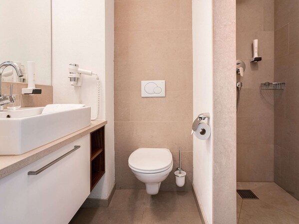 A modern bathroom with a white sink, toilet, and shower.