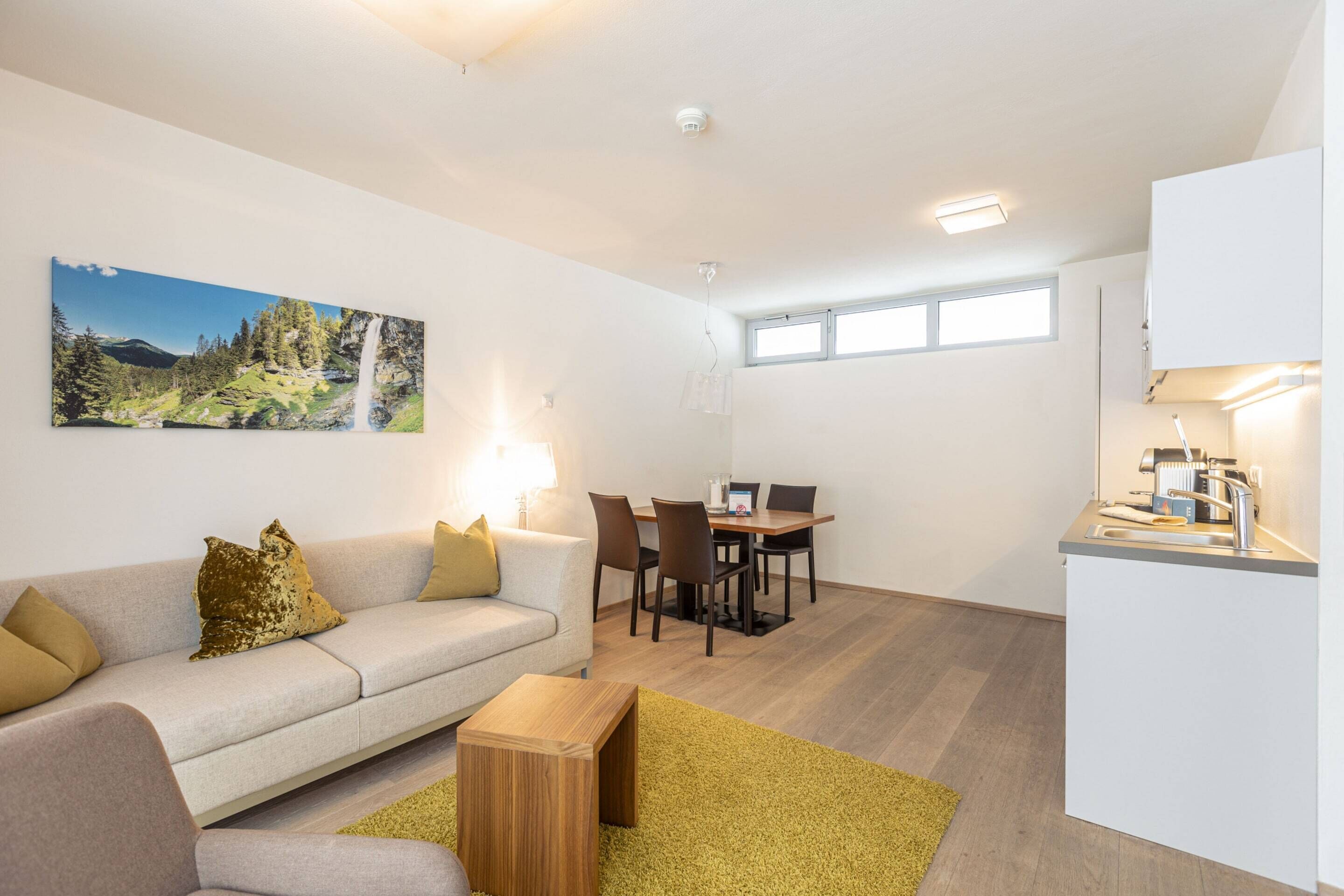 A modern living room with a sofa, coffee table, and a dining area with chairs and a table.