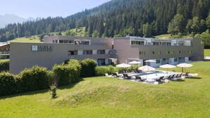 A modern building with a sign reading "TAUERN RESIDENCE". It has a pool area with lounge chairs and umbrellas. - Nice Apartment With Dishwasher, Near the Ski Slopes (Radstadt)