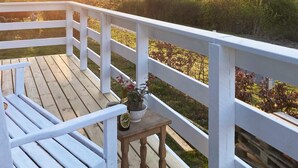 A wooden deck with a white railing, a small table with a potted plant, and a bottle of beer. - 6 Person Holiday Home in Rude (Bisserup)